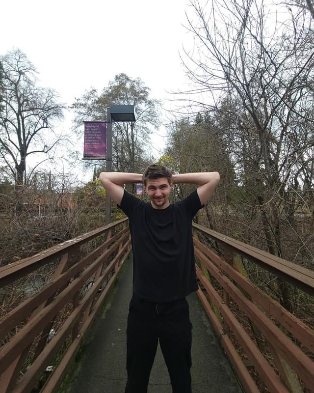 Conor standing on a footbridge with his hands behind his head